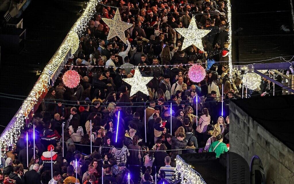 Des fêtards, le 11 décembre 2022, se massent pour assister à la cérémonie d’illumination du sapin de Noël près de la porte Jaffa de la Vieille Ville de Jérusalem. (Crédit : Ahmad Gharabli/AFP) Des fêtards, le 11 décembre 2022, se massent pour assister à la cérémonie d’illumination du sapin de Noël près de la porte Jaffa de la Vieille Ville de Jérusalem. (Crédit : Ahmad Gharabli/AFP)