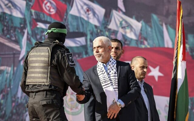 Yaha Sinwar, chef du groupe terroriste du Hamas dans la bande de Gaza, serre la main d'un combattant masqué de l'aile militaire lors d'un rassemblement marquant le 35e anniversaire de la fondation du groupe, dans la ville de Gaza, le 14 décembre 2022. (Crédit : MOHAMMED ABED / AFP) Yaha Sinwar, chef du groupe terroriste du Hamas dans la bande de Gaza, serre la main d'un combattant masqué de l'aile militaire lors d'un rassemblement marquant le 35e anniversaire de la fondation du groupe, dans la ville de Gaza, le 14 décembre 2022. (Crédit : MOHAMMED ABED / AFP)