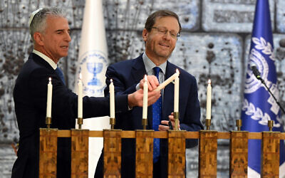 Le président Isaac Herzog (à droite) et le chef du Mossad David Barnea allument la Hanoukka à la Maison du président, le 22 décembre 2022. (Crédit : Haim Tzach/GPO)