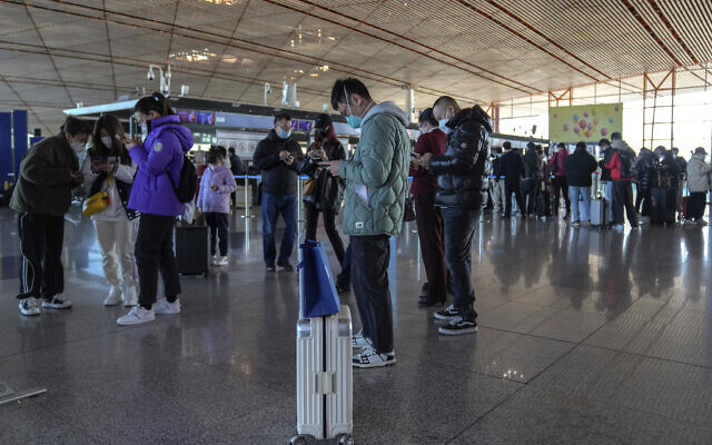 Des voyageurs masqués utilisent leurs smartphones pour remplir leur déclaration de santé après s'être enregistrés au comptoir d'enregistrement des vols internationaux à l'aéroport international de la capitale de Pékin, jeudi 29 décembre 2022. (Crédit : Andy Wong/AP) Des voyageurs masqués utilisent leurs smartphones pour remplir leur déclaration de santé après s'être enregistrés au comptoir d'enregistrement des vols internationaux à l'aéroport international de la capitale de Pékin, jeudi 29 décembre 2022. (Crédit : Andy Wong/AP)
