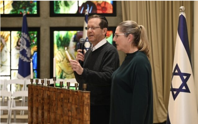 Le président Isaac Herzog allumant la première bougie de Hanoukka aux côtés de son épouse, Michal, à la résidence présidentielle, le 18 décembre 2022. (Crédit : Haim Zach/GPO)