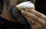 Illustration : Un homme mangeant une soufganiyah, un beignet traditionnel de Hanoukka, quelques jours avant la fête des Lumières, à Kiryat Shmona, dans le nord d'Israël, le 14 décembre 2022. (Crédit : Ayal Margolin/Flash90)