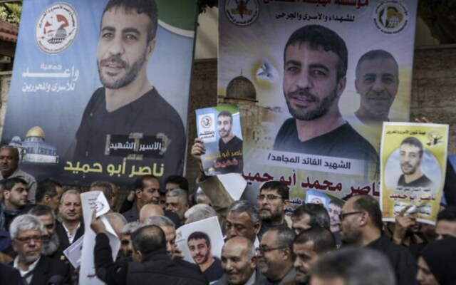 Des personnes se rassemblant avec des photos du Palestinien Nasser Abu Hamid pour une manifestation devant le siège de la mission du Comité international de la Croix-Rouge (CICR) dans la ville de Gaza, le 20 décembre 2022. (Crédit : Mahmud Hams/AFP)