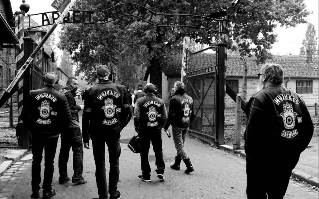 Des membres de la MuJu & Co. passant sous le tristement célèbre panneau "Le travail vous rendra libre" au musée-mémorial d'Auschwitz-Birkenau en Pologne, le 1er octobre 2022. (Crédit : Dan Meyrowitsch)