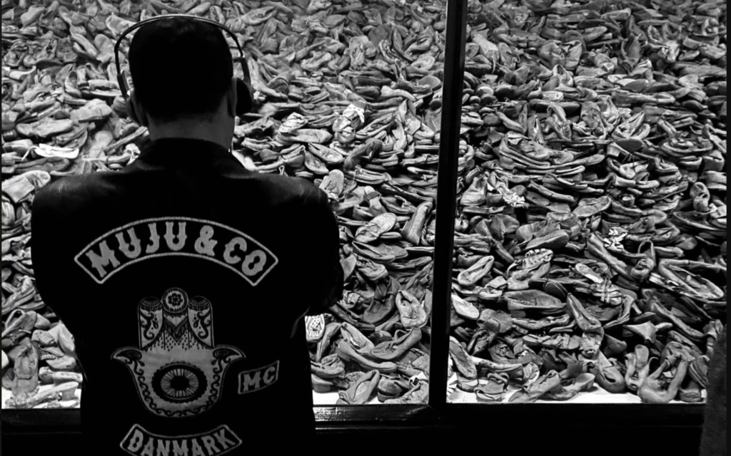  Un membre du club de moto MuJu & Co. regardant des chaussures de victimes d'Auschwitz, lors de leur visite au mémorial du camp de concentration, le 1er octobre 2022. (Crédit : Dan Meyrowitsch)
