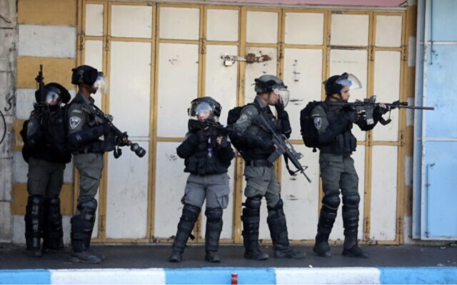 Des agents de la police des frontières en tenue anti-émeute se heurtant à des Palestiniens dans la ville de Hébron, en Cisjordanie, le 12 octobre 2022. (Crédit : Wisam Hashlamoun/Flash90)
