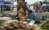 Sur cette photo prise le 21 septembre 2022, une ancienne "devadasi" place une guirlande de fleurs sur un masque décoré de la déesse hindoue Yellamma Devi près d'un étang où les femmes "devadasis" qui étaient vouées par leur famille à la déesse hindoue Yellamma Devi, se purifient avant de visiter le temple de Yellamma Devi à Savadatti dans le district de Belgaum, dans l'État indien du Karnataka. (Crédit : Manjunath Kiran / AFP)