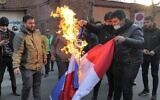 Des manifestants brûlent un drapeau français lors d'une manifestation contre des caricatures du guide suprême de la République islamique, l'ayatollah Ali Khamenei, publiées par l'hebdomadaire satirique français Charlie Hebdo, devant l'ambassade de France à Téhéran, la capitale iranienne, le 8 janvier 2023. (Crédit : ATTA KENARE/AFP)