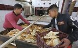 Un jeune Irakien achète des pains fraîchement cuits dans une boulangerie de pain Samoun dans la rue al-Rashid, à Bagdad, la capitale de l'Irak, le 11 janvier 2023. (Crédit : Sabah ARAR / AFP)