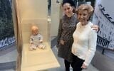 Lore Mayerfeld (R) et sa petite-fille Shani Stringer posent à côté d'une poupée blonde de 80 ans exposée lors de l'inauguration de l'exposition 16 objets 70 ans de Yad Vashem au bâtiment parlementaire Paul-Loebe-Haus à Berlin, le 24 janvier 2023. (Crédit : Julien GATHELIER / AFP)