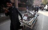 Des Pakistanais poussent une civière transportant une victime blessée, dans un hôpital de Peshawar, le 30 janvier 2023, après l'explosion la veille d'une mosquée située à l'intérieur du quartier général de la police de Peshawar, dans le nord-ouest du Pakistan. (Crédit : Zafar IQBAL/AFP)