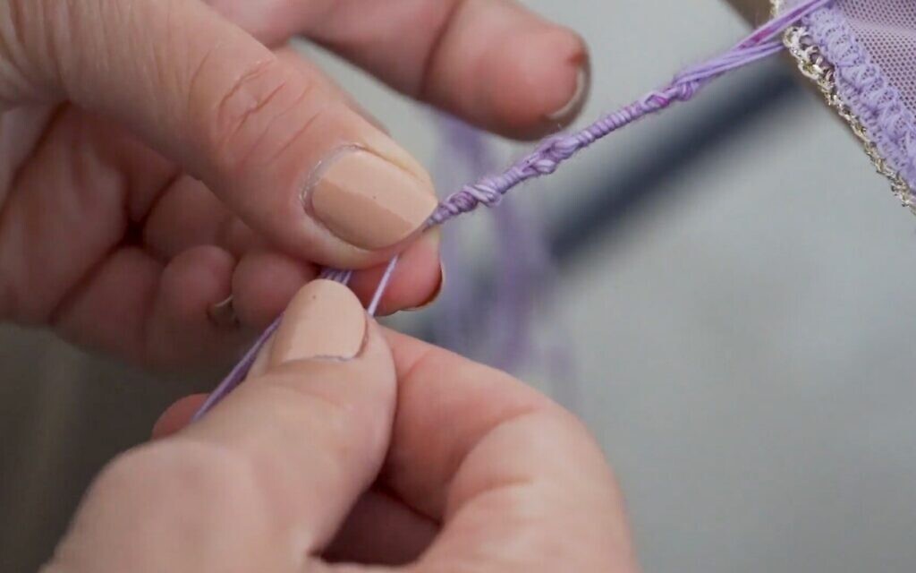 L'artiste Julie Weitz fait les nœuds des tzitzit. (Crédit : Autorisation de Tzitzit Project/JTA)