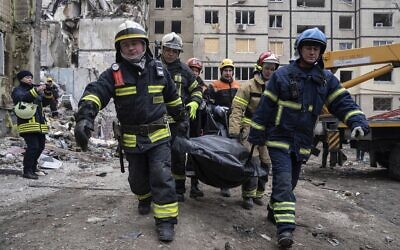 Des secouristes transportent le corps d'un homme qui a été tué lors d'un tir de missile russe sur un immeuble d'habitation dans la ville de Dniepr, au sud-est de l'Ukraine, lundi 16 janvier 2023. (Crédit : AP Photo/Evgeniy Maloletka)
