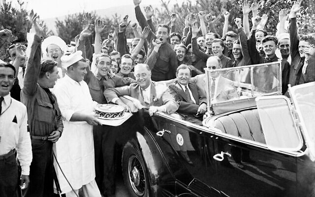 Le président Franklin D. Roosevelt reçoit un gâteau des mains des chefs du Civil Conservation Corps en l'honneur de sa visite au camp de Bear Mountain, dans l'Etat de New York, le 27 août 1933. Se trouvent avec Roosevelt le superindendent du Parc de Palisades, le Major William Welch, au centre, et le directeur du Service du crédit agricole, Henry Morgenthau, à droite. (Crédit : AP Photo)
