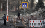 Des personnes se tenant à côté d'un bâtiment démoli suite à une frappe russe sur Kiev, en Ukraine, le 31 décembre 2022. (Crédit : AP Photo/Efrem Lukatsky)