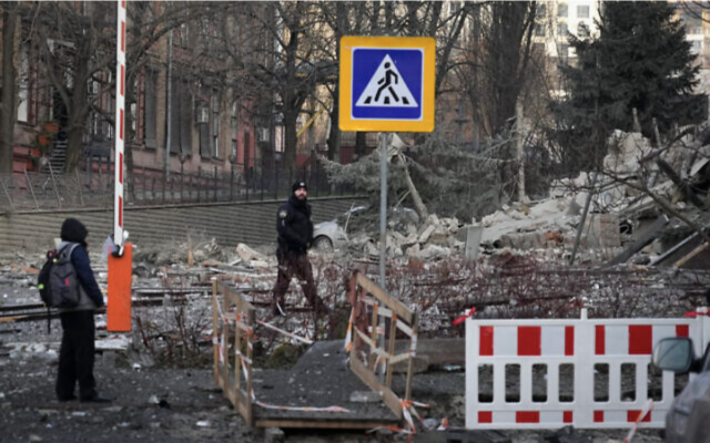 Des personnes se tenant à côté d'un bâtiment démoli suite à une frappe russe sur Kiev, en Ukraine, le 31 décembre 2022. (Crédit : AP Photo/Efrem Lukatsky)