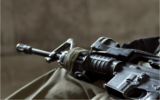 Illustration : Un fusil d'assaut sur les genoux d'un soldat israélien. (Crédit : Vanish_Point/iStock by Getty Images)