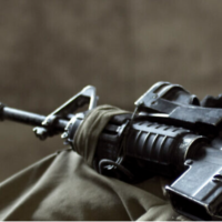 Illustration : Un fusil d'assaut sur les genoux d'un soldat israélien. (Crédit : Vanish_Point/iStock by Getty Images)