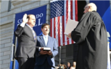 Brian Boatright, le juge en chef de la Cour suprême du Colorado, à droite, prêtant serment au gouverneur Jared Polis, à gauche, tandis que le mari de Polis, Marlon Reis, tient un Tanakh, à Denver, le 10 janvier 2023. (Crédit : Compte Facebook du gouverneur Jared Polis via JTA)