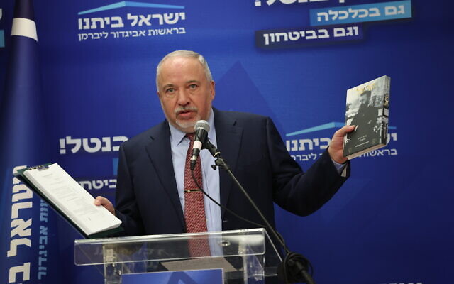 Le leader du parti Yisrael Beytenu, Avigdor Liberman, tenant dans sa main droite une copie des accords de coalition récemment signés et dans sa main gauche une copie d'un livre de Theodor Herzl, lors d'une réunion de faction à la Knesset, à Jérusalem, le 2 janvier 2023. (Crédit : Yonatan Sindel/Flash90)