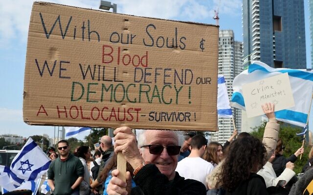 Des manifestants israéliens brandissent des drapeaux nationaux et des pancartes à Tel Aviv le 13 février 2023, lors d'une manifestation contre les réformes juridiques controversées avancées par le gouvernement. (Crédit : JACK GUEZ / AFP)