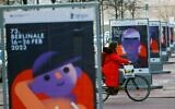 Une femme passe devant une rangée d'affiches pour le 73e Festival international du film de la Berlinale à Berlin, le 15 février 2023. (Crédit : David GANNON / AFP)