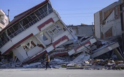 Un homme marche devant un bâtiment détruit à Samandag, au sud de Hatay, le 16 février 2023, dix jours après qu'un séisme de magnitude 7,8 ait frappé la région frontalière de la Turquie et de la Syrie. (Crédit : Yasin AKGUL / AFP)