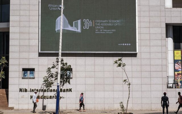 Des passants devant un panneau électronique annonçant  la 36e session ordinaire de l'Assemblée de l'Union africaine (UA) au siège de l'organisation à Addis Ababa, le 18 février 2023. (Crédit : Amanuel Sileshi / AFP)