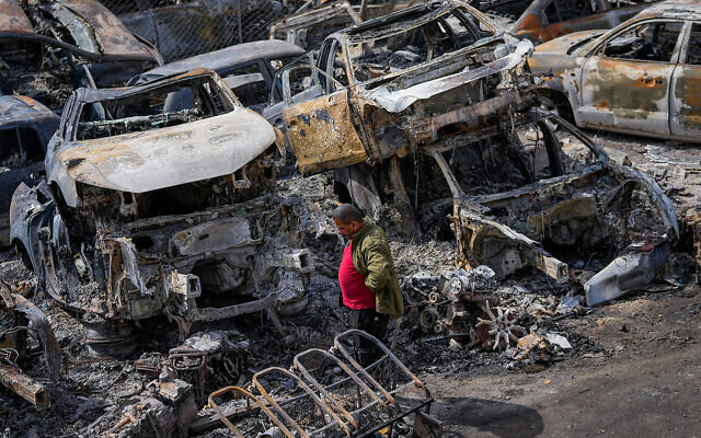 Un Palestinien marche entre des voitures brûlées dans une casse après une émeute des habitants, dans la ville de Huwara, près de la ville de Naplouse en Cisjordanie, le 27 février 2023. (Crédit : Ohad Zwigenberg/AP) Un Palestinien marche entre des voitures brûlées dans une casse après une émeute des habitants, dans la ville de Huwara, près de la ville de Naplouse en Cisjordanie, le 27 février 2023. (Crédit : Ohad Zwigenberg/AP)