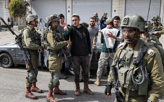 Des soldats israéliens parlant avec des résidents d’implantations dans la ville de Huwara, près de Naplouse, en Cisjordanie, le 27 février 2023. (Crédit : Ronaldo Schemidt/AFP) Des soldats israéliens parlant avec des résidents d’implantations dans la ville de Huwara, près de Naplouse, en Cisjordanie, le 27 février 2023. (Crédit : Ronaldo Schemidt/AFP)