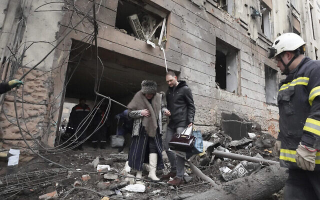 Illustration : Un homme aide une femme à sortir d’un bâtiment touché par une roquette russe, dans le centre-ville de Kharkiv, en Ukraine, le 5 février 2023. (Crédit : AP Photo/Andrii Marienko)