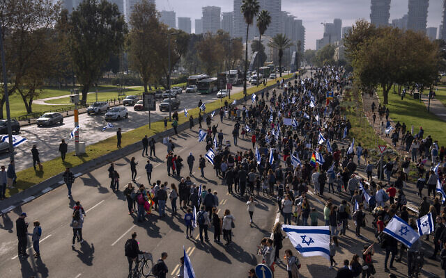 Des Israéliens agitent des drapeaux nationaux lors d'un rassemblement contre les plans du nouveau gouvernement du Premier ministre Benjamin Netanyahu visant à remanier le système judiciaire, à Tel Aviv, en Israël, le 13 février 2023. (Crédit : AP Photo/Oded Balilty) Des Israéliens agitent des drapeaux nationaux lors d'un rassemblement contre les plans du nouveau gouvernement du Premier ministre Benjamin Netanyahu visant à remanier le système judiciaire, à Tel Aviv, en Israël, le 13 février 2023. (Crédit : AP Photo/Oded Balilty)