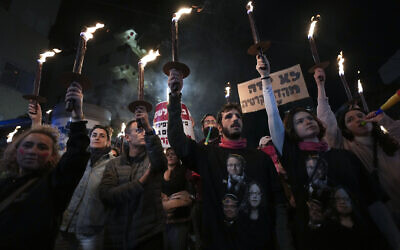  Des Israéliens portant des torches lors d'une manifestation contre les projets du gouvernement du Premier ministre Benjamin Netanyahu de remanier le système judiciaire, à Tel Aviv, en Israël, le 18 février 2023. (Crédit : AP Photo/Tsafrir Abayov)