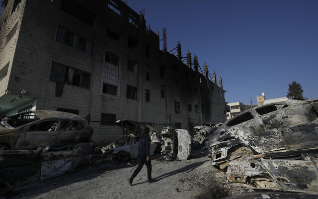 Un Palestinien passe devant des voitures brûlées dans la ville de Huwara, près de la ville de Naplouse en Cisjordanie, le 27 février 2023. (Crédit : AP Photo/Majdi Mohammed)