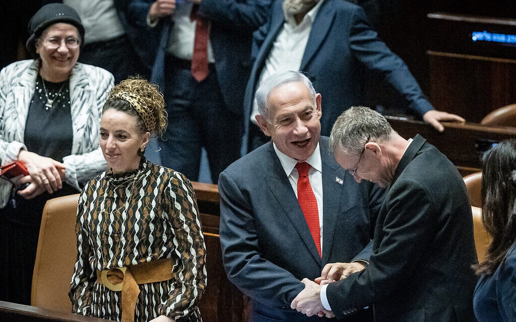Le Premier ministre Benjamin Netanyahu serrant la main du ministre de la Justice, Yariv Levin, sous le regard d'autres membres de la coalition, après un vote sur les projets de réforme du système judiciaire du gouvernement, à la Knesset, le 21 février 2023. (Crédit : Yonatan Sindel/Flash90) Le Premier ministre Benjamin Netanyahu serrant la main du ministre de la Justice, Yariv Levin, sous le regard d'autres membres de la coalition, après un vote sur les projets de réforme du système judiciaire du gouvernement, à la Knesset, le 21 février 2023. (Crédit : Yonatan Sindel/Flash90)