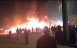 Des résidents d'implantations regardant des voitures et des maisons qu'ils ont incendiées dans la ville de Huwara, en Cisjordanie, le 26 février 2023. (Crédit : Twitter)