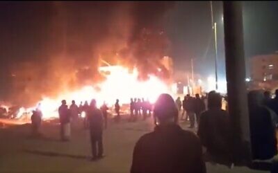 Des résidents d'implantations regardant des voitures et des maisons qu'ils ont incendiées dans la ville de Huwara, en Cisjordanie, le 26 février 2023. (Crédit : Twitter)