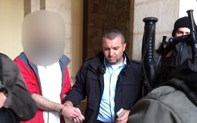 Un touriste américain, à gauche, est emmené par la police qui le soupçonne d'avoir vandalisé une statue dans la chapelle de la Condamnation dans la vieille ville de Jérusalem, le 2 février 2023. (Crédit : Police israélienne)