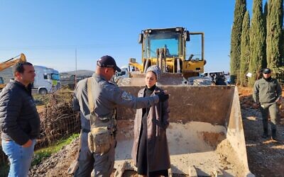 La députée Otzma Yehudit, Limor Son Har Melech, se tenant devant un bulldozer sur un terrain près de l'implantation de Shiloh en Cisjordanie afin d'arrêter le déracinement des arbres par l'Administration civile du ministère de la Défense, le 15 février 2023. (Crédit : Bureau de Limor Son Har Melech)