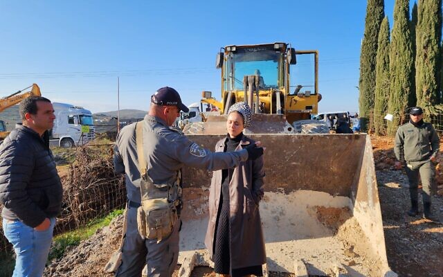 La députée Otzma Yehudit, Limor Son Har Melech, se tenant devant un bulldozer sur un terrain près de l'implantation de Shiloh en Cisjordanie afin d'arrêter le déracinement des arbres par l'Administration civile du ministère de la Défense, le 15 février 2023. (Crédit : Bureau de Limor Son Har Melech) La députée Otzma Yehudit, Limor Son Har Melech, se tenant devant un bulldozer sur un terrain près de l'implantation de Shiloh en Cisjordanie afin d'arrêter le déracinement des arbres par l'Administration civile du ministère de la Défense, le 15 février 2023. (Crédit : Bureau de Limor Son Har Melech)