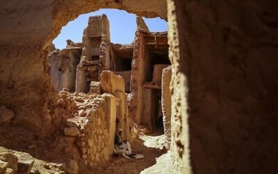 Une femme est assise dans une ruelle du quartier juif, ou mellah, du village de Tagadirt dans la région oasienne de Tata au Maroc, le 28 février 2023. (Crédit : FADEL SENNA / AFP)