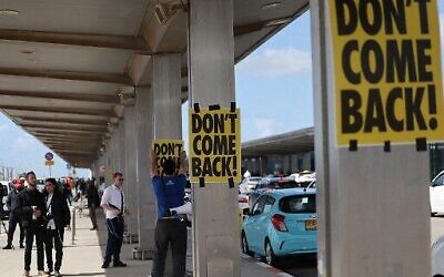 Un manifestant anti-gouvernement accroche une affiche avec le slogan "Ne revenez pas" à l'aéroport Ben Gurion, pendant un rassemblement contre la réforme judiciaire controversée, près de Tel Aviv, le 15 mars 2023. (Crédit :  AHMAD GHARABLI / AFP)