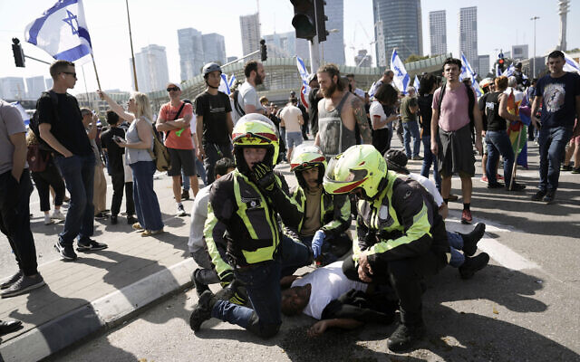 Des secouristes soignent un homme blessé après le déploiement de policiers à cheval et l'utilisation de grenades assourdissantes pour disperser des manifestants qui bloquaient une route principale pour protester contre le projet du gouvernement de réformer le système judiciaire, à Tel Aviv, en Israël, le 1er mars 2023. (Crédit : Oded Balilty/AP) Des secouristes soignent un homme blessé après le déploiement de policiers à cheval et l'utilisation de grenades assourdissantes pour disperser des manifestants qui bloquaient une route principale pour protester contre le projet du gouvernement de réformer le système judiciaire, à Tel Aviv, en Israël, le 1er mars 2023. (Crédit : Oded Balilty/AP)