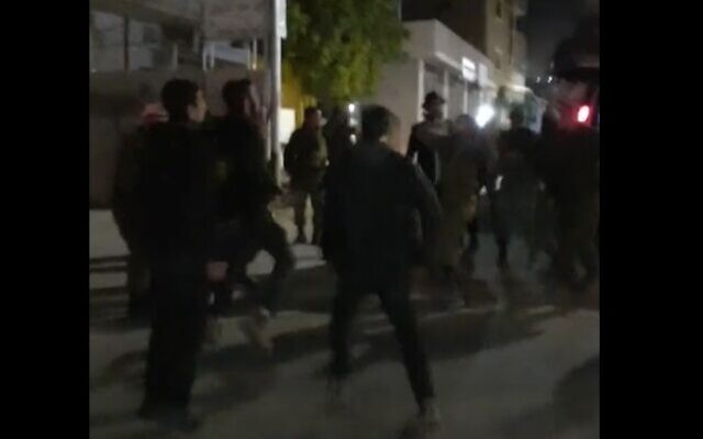 Des habitants des implantations célébrant Pourim dansent avec les troupes de Tsahal dans la ville de Huwara en Cisjordanie, le 6 mars 2023. (Crédit : Capture d'écran/Twitter ; utilisé conformément à la clause 27a de la loi sur le droit d'auteur) Des habitants des implantations célébrant Pourim dansent avec les troupes de Tsahal dans la ville de Huwara en Cisjordanie, le 6 mars 2023. (Crédit : Capture d'écran/Twitter ; utilisé conformément à la clause 27a de la loi sur le droit d'auteur)