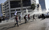  La police déployant un canon à eau pour disperser des manifestants qui bloquent une route principale pour protester contre les projets du gouvernement de remanier le système judiciaire, à Tel Aviv, en Israël, le 1er mars 2023. (Crédit : Oded Balilty/AP)