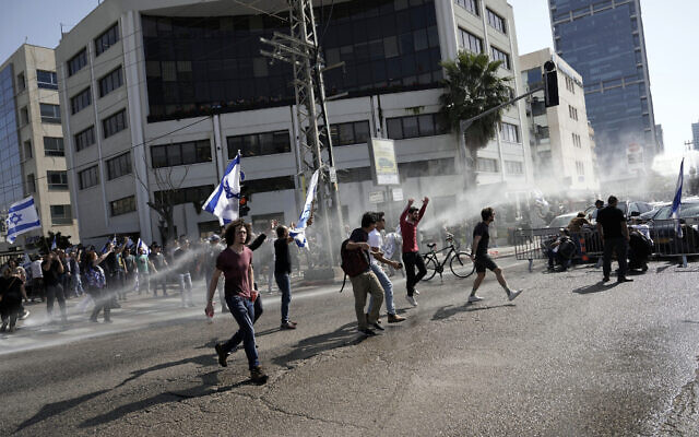  La police déployant un canon à eau pour disperser des manifestants qui bloquent une route principale pour protester contre les projets du gouvernement de remanier le système judiciaire, à Tel Aviv, en Israël, le 1er mars 2023. (Crédit : Oded Balilty/AP)