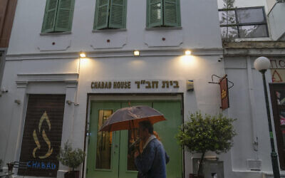 Un homme tenant un parapluie devant un restaurant juif dont les autorités grecques pensent qu'il a été l'une des cibles d'un projet d'attentat terroriste, dans le centre d'Athènes, le 28 mars 2023. (Crédit : AP Photo/Thanassis Stavrakis)