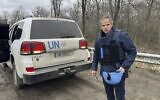 Le chef de l'Agence internationale pour l'énergie atomique, Rafael Mariano Grossi, se tenant sur une route à côté d'un véhicule de l'ONU alors qu'il se rend à la centrale nucléaire de Zaporijjia, dans le sud-est de l'Ukraine, le 29 mars 2023. (Crédit : Bureau de presse de l'AIEA via AP)