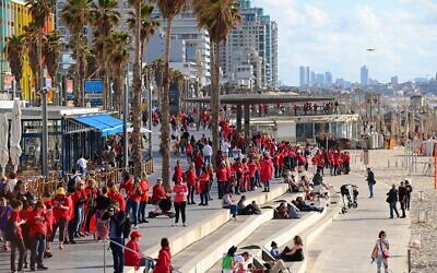 Des centaines de femmes vêtues de rouge marquant la Journée internationale de la femme et manifestant contre la réforme du système judiciaire prévue par le gouvernement, sur la plage de Tel Aviv, le 8 mars 2023. (Crédit : Tomer Neuberg/Flash90)