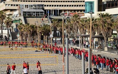 Des centaines de femmes vêtues de rouge marquant la Journée internationale de la femme et manifestant contre la réforme du système judiciaire prévue par le gouvernement, sur la plage de Tel Aviv, le 8 mars 2023. (Crédit : Tomer Neuberg/Flash90)